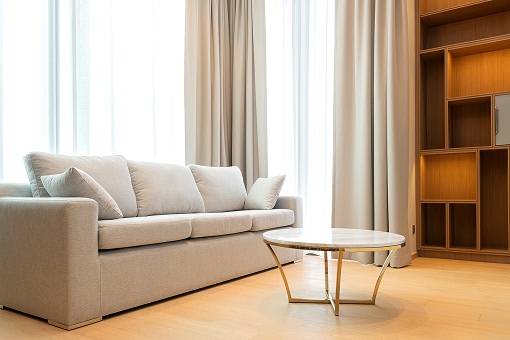 close-up-light-beige-fabric-sofa-with-warm-cozy-morning-light-from-big-window-home-interior-background 1